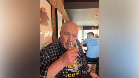 Family handouts A man sniffs a wine glass in a pub