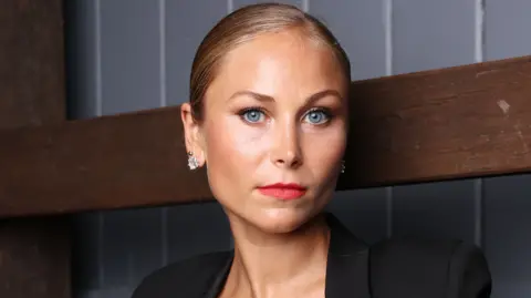 A blonde woman with blue eyes and red lipstick