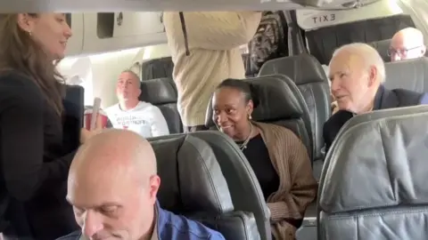 Joe Biden is seen inside an airplane with other passengers.