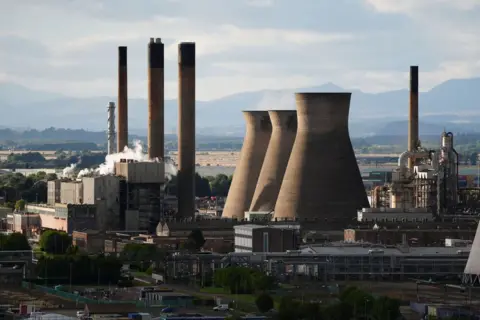 PA media is an oil refinery with an oil refinery that emit smoke. The mountains are seen in the background.