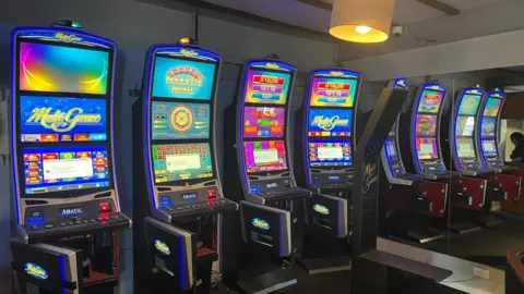 A picture of several gambling machines at the venue in Sheffield. The bottom compartment, where the money is stored, is open on all of them.