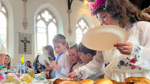 Children in a line with paper plates picking food from a buffet