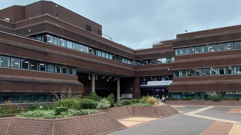 Local Democracy Reporting Service A building of at least three storeys, with the image showing one part of the building on the left at right angles to another part of the building on the right. An area for pedestrians is in the foreground.