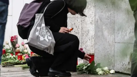 EPA woman lays flowers at the scene on Tuesday