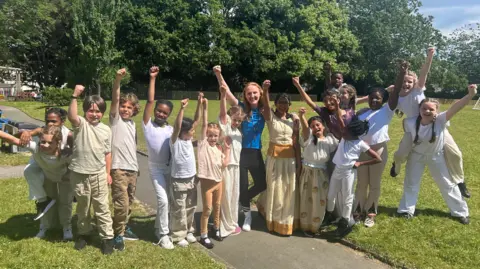 Photograph of pupils at St David's catholic school. They all stand in a row in a park.
