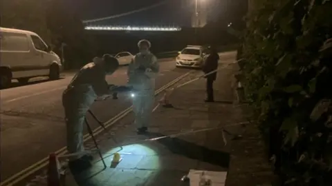 People in white suits examining potential evidence in Sion Hill