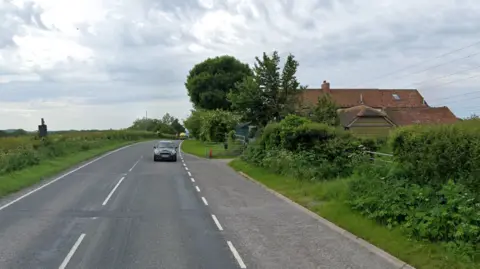 Google View down Hinkley Point Road, with a terracotta-roofed house with a gate to the right and a low hedge to the left.