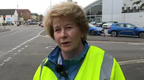 BBC Councillor Lesley McLean, who has short, blonde hair, is wearing a hi-vis jacket and has a light blue waterproof coat under that