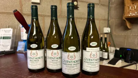 Four bottles of white wine with the label "Leventhorpe" stand on a bar top in a vineyard's office in Leeds.