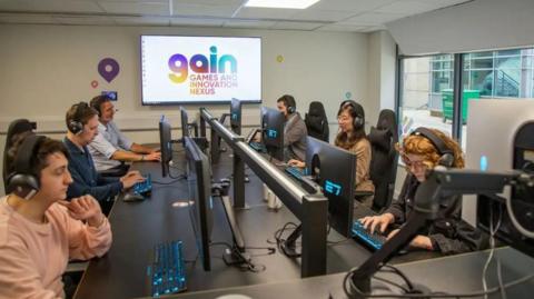 Six people sit at computers