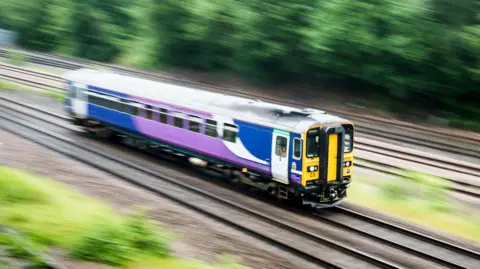 A Northern train travelling fast on a track in Leeds.