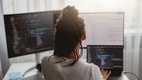 Stock image of a woman looking at code on a screen
