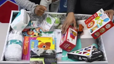 A view inside the baby box, showing toys, towels, books and blankets 