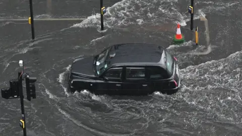Getty Images A black cab drives through flooded road