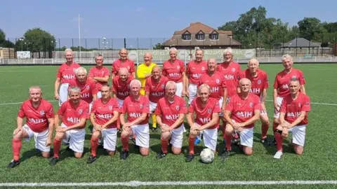 Geoff Martel The England over-75s football team are seen on the pitch in a squad formation wearing red tops and white shorts with red football socks 