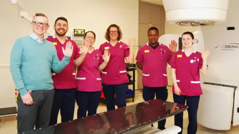 Northampton General Hospital The radiotherapy team with the new Linear Accelerator L-R Mark Cowen, Stephen Fuller, Kayleigh Dawes, Erika Browett, Robson Mango, and Lauren Cox.