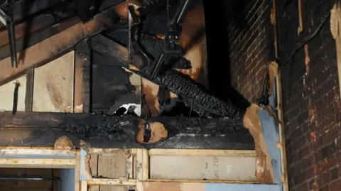 Dawid Wojtowicz/BBC Part of the timber ceiling at the museum is blackened by fire damage.