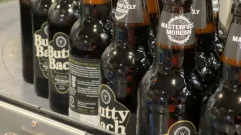 Bottles of Butty Bach, Wye Valley Brewery's best-selling beer, bunch together on a conveyor belt in the firm's bottling plant. 