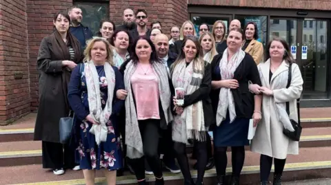 Brian Farmer/BBC A group of people gathered on the steps of Aylesbury Crown Court - a red-bricked building with black-framed entrance doors.