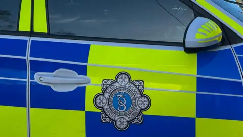 The side of a marked police car with the logo of An Garda Síochána