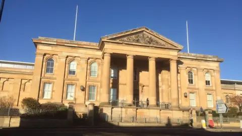 The exterior of a court building, with four large columns at the front of the building