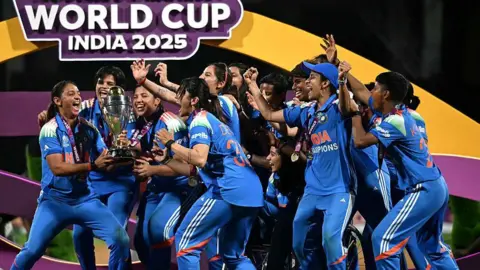 AFP via Getty Images Players of Team India celebrate and lift the World Cup trophy during the ICC Women's Cricket World Cup India 2025 Final
