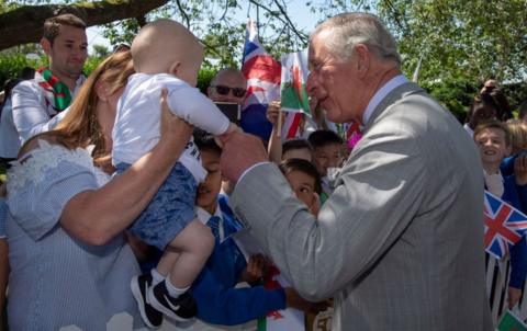 King Charles in July 2019 greeting a baby as he visits Victoria Park and the Patti Pavilion for a celebration of the 50th anniversary of Swansea's City status.