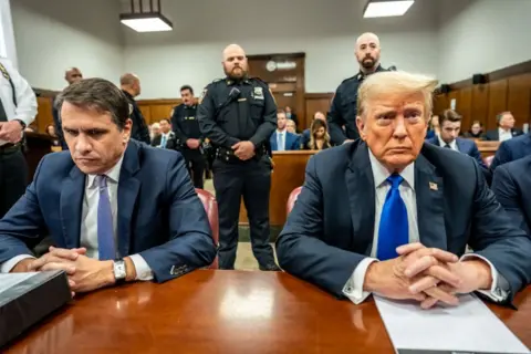 Getty Images Todd Blanche and Donald Trump, both wearing suits with blue ties, rest their hands on a table in a courtroom in New York