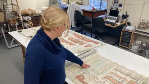 Sarah Chubb points at designs of a school on a map