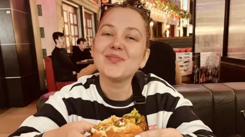 Family photograph Woman in restaurant in black and white striped jumper eating hamburger