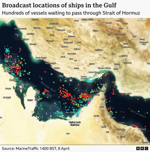 A satellite image of the Strait of Hormuz with ships marked with arrows. It shows hundreds of ships clustered by the strait waiting to pass. It is timestamped to 14:00BST on 8 April