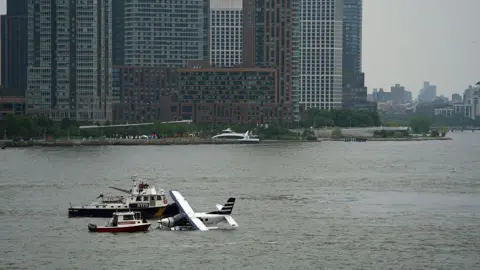Getty Images Emergency services respond to a crashed seaplane in the East River on 5 July in New York City.
