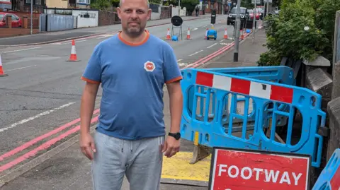 LDRS Resident David Broome stood by roadworks signs on City Road