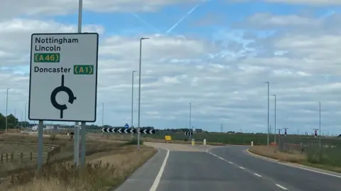Part of newly built road with sign indication way to A46 and A1
