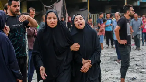 Palestinians react after an Israeli air strike on a UN school in Nuseirat refugee camp, in central Gaza (6 June 2024)