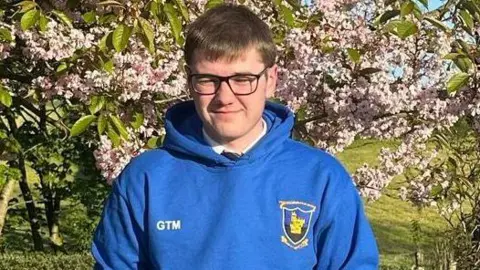 Handout George McCurdy has glasses and has dark hair. He is wearing a blue hoodie and is looking at the camera. 