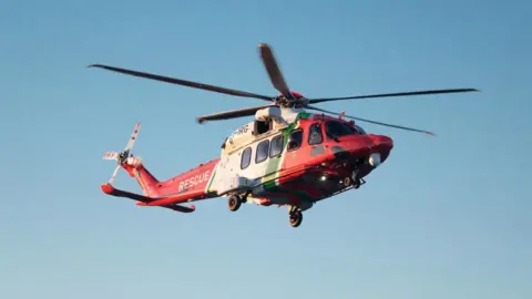 Bristow Helicopters/IRCG A red and white Irish Coast Guard helicopter flying in a clear blue sky. 
