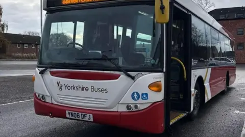 A parked bus owned by firm Yorkshire Buses in a red and white livery.
