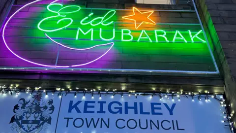 Eid Mubarak written in green neon lights with a white sign underneath that says Keighley Town Council
