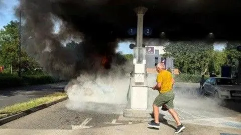  a man with a fire extinguisher running towards the Pontiac Firebird which is on fire. There is a lot of smoke.