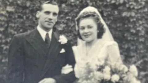 Phyliss Marshall Phyliss Marshall's wedding photo taken in 1948, she is pictured wearing her white dress with a large collar and veil holding a bouquet of flowers. Both are arm in arm.