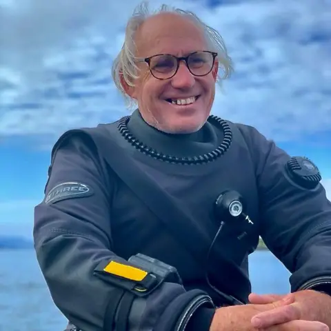 Scottish Maritime Museum Graeme Bruce, a man with grey hair in his diving gear after recovering the treasure from the SS Eagle