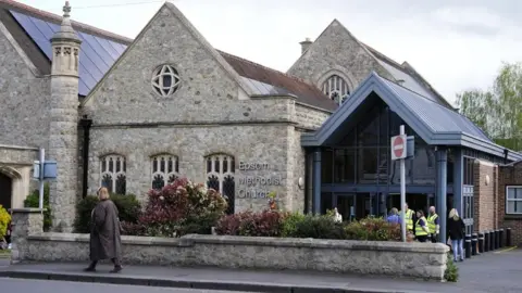A church built with stone. There is a sign in front of the building.