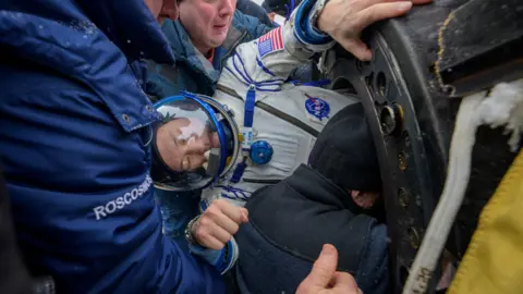 NASA astronaut Jonny Kim receives assistance from specialists while getting out of the Soyuz MS-27 space capsule