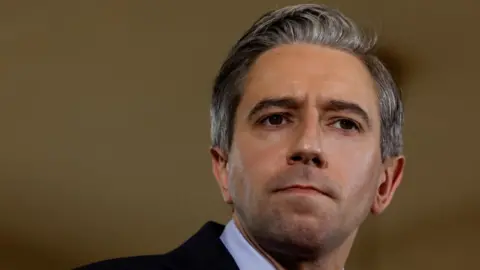 Reuters Harris is looking away from the camera. He has greying hair and is wearing a dark coloured suit jacket and a white shirt.