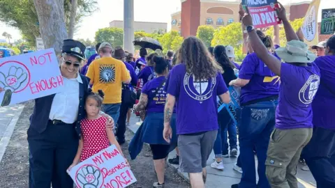 Disneyland train conductor Cecilia Quail poses with her granddaughter during a protest outside the park. 