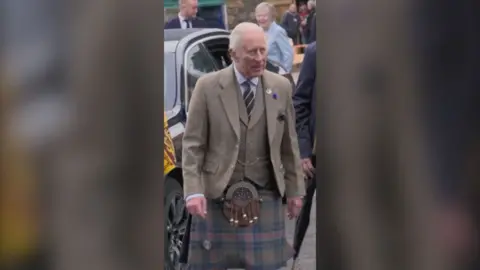 King Charles wearing a tweed jacket and a kilt