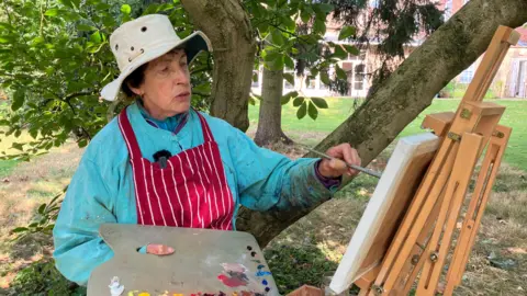 Sam Read/BBC Virginia Albutt paints at an easel