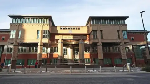 The exterior of Sheffield Crown Court - a modern redbrick building pictured in dim sunlight.