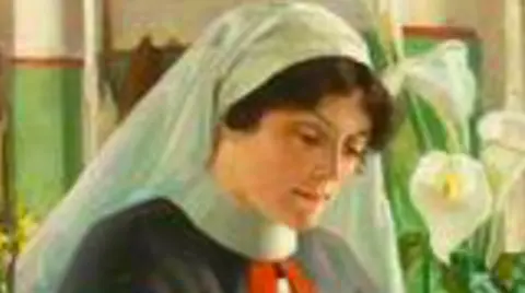 Cardiff and Vale University Health Board Sister Mary Jones is applying a bandage to the patient's head. She is dressed very similarly to the matron, except she has a white apron over her uniform. She is a young woman with brown curly hair tied back under the nurse's cap